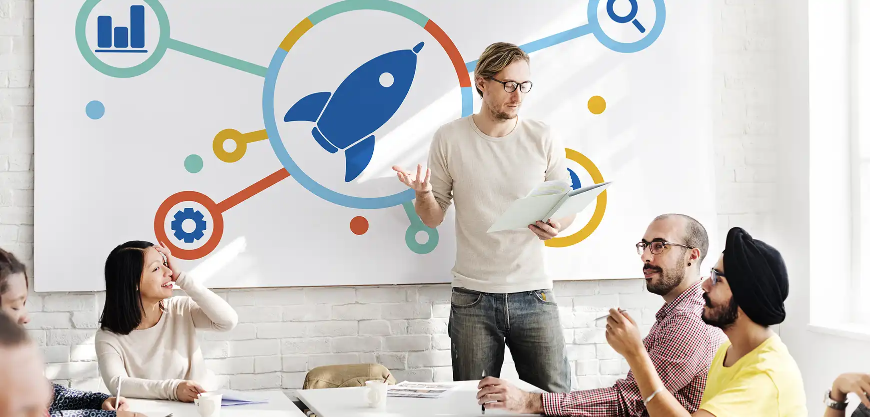 Group of people in a meeting with a person doing a presentation pitching ideas and solutions.